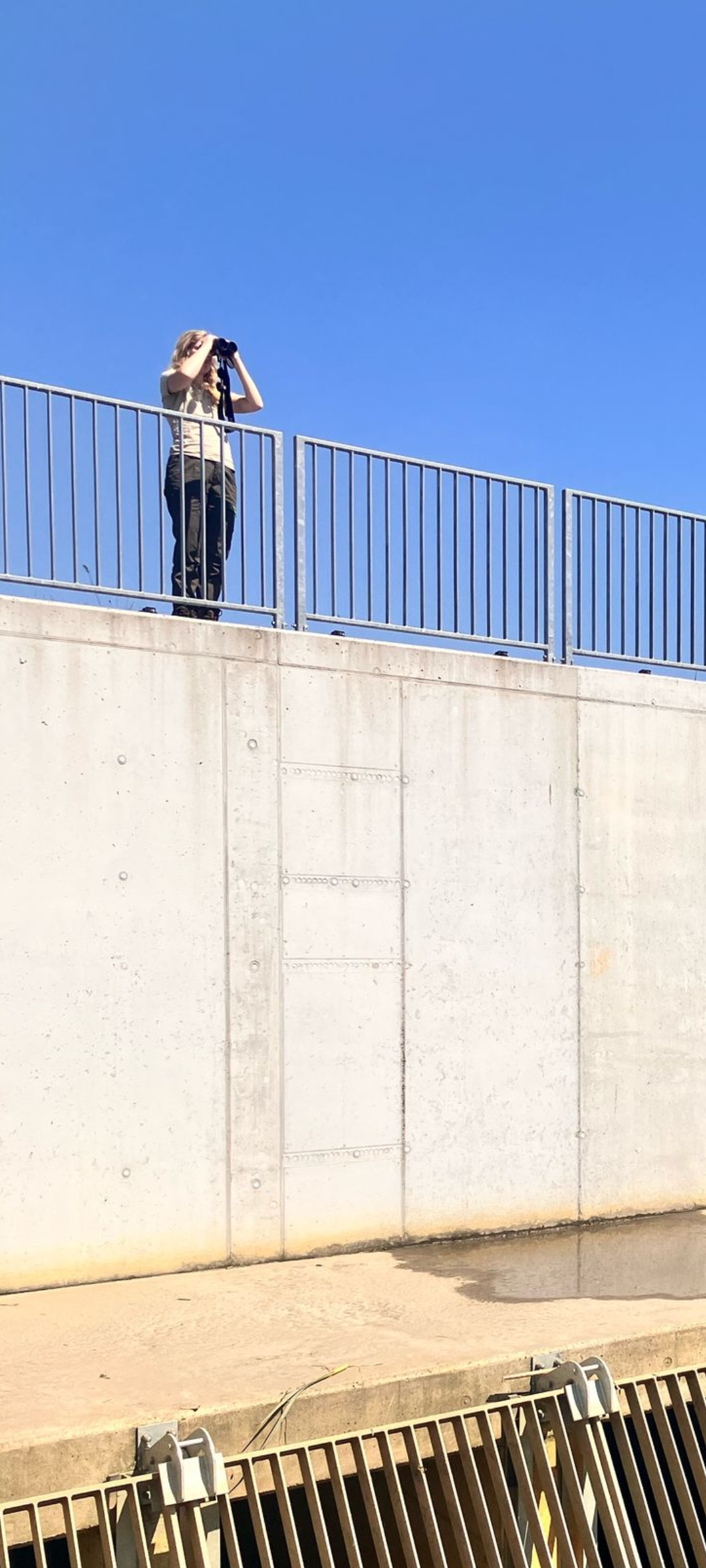 vrouw met verrekijker op dam